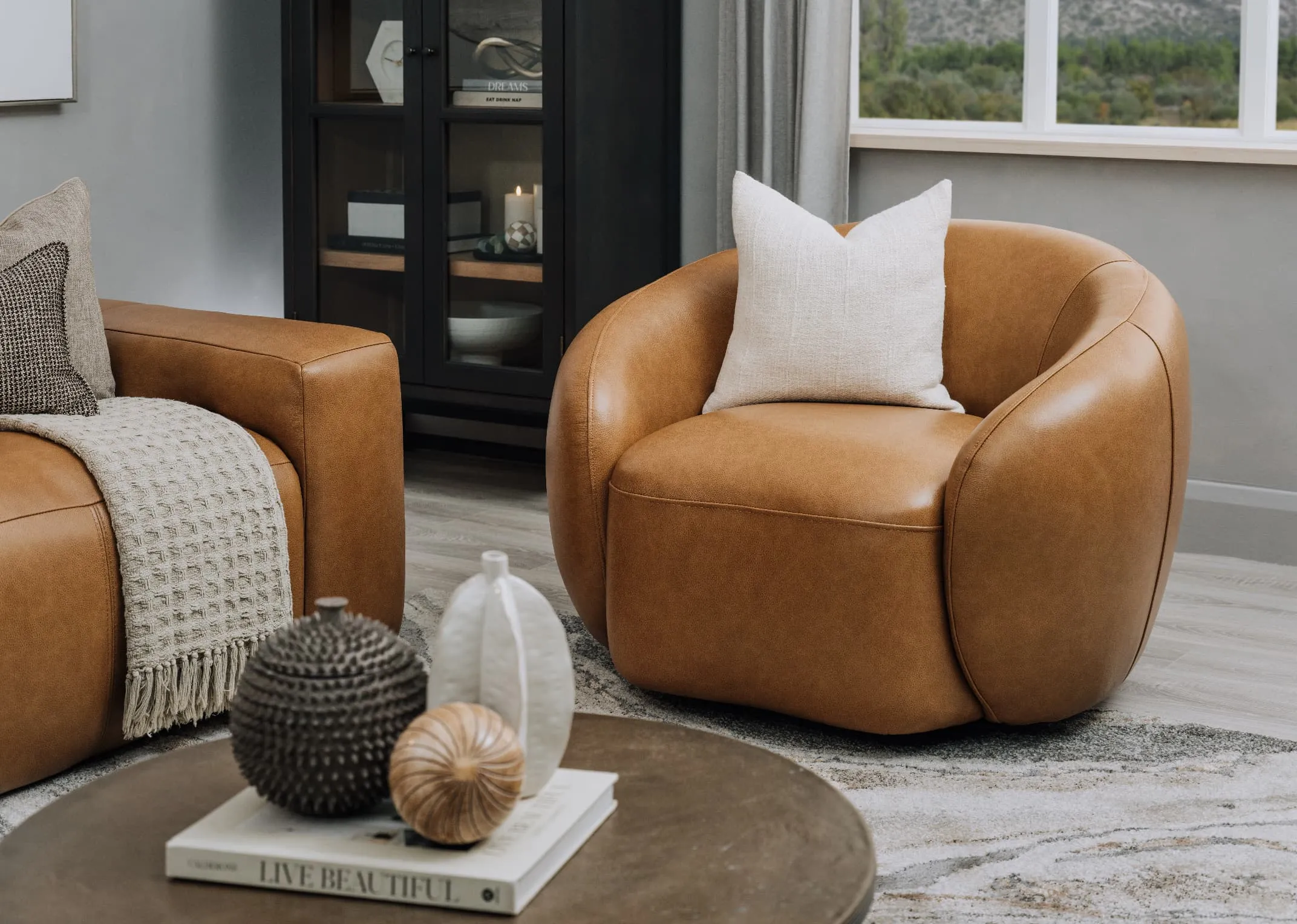 A lifestyle image of the Danica leather swivel chair with cream linen cushion with Breeze tables