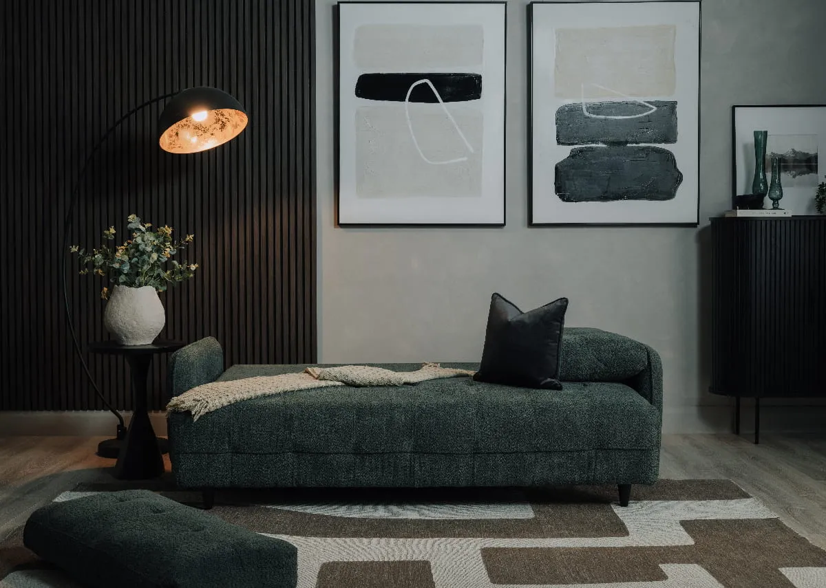 A lifestyle image of the Merrion sofabed as a bed with cushions and Elite floor lamp with Mode & Intense canvas pics.