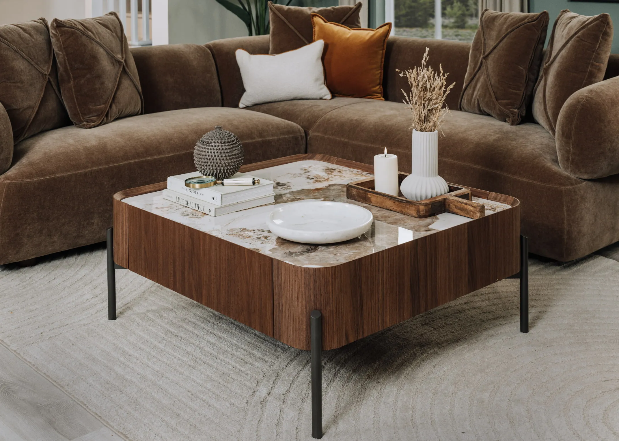 A lifestyle image of the Century coffee table with marble top and marble dished and tray with candles teamed with the Carla Chaise.