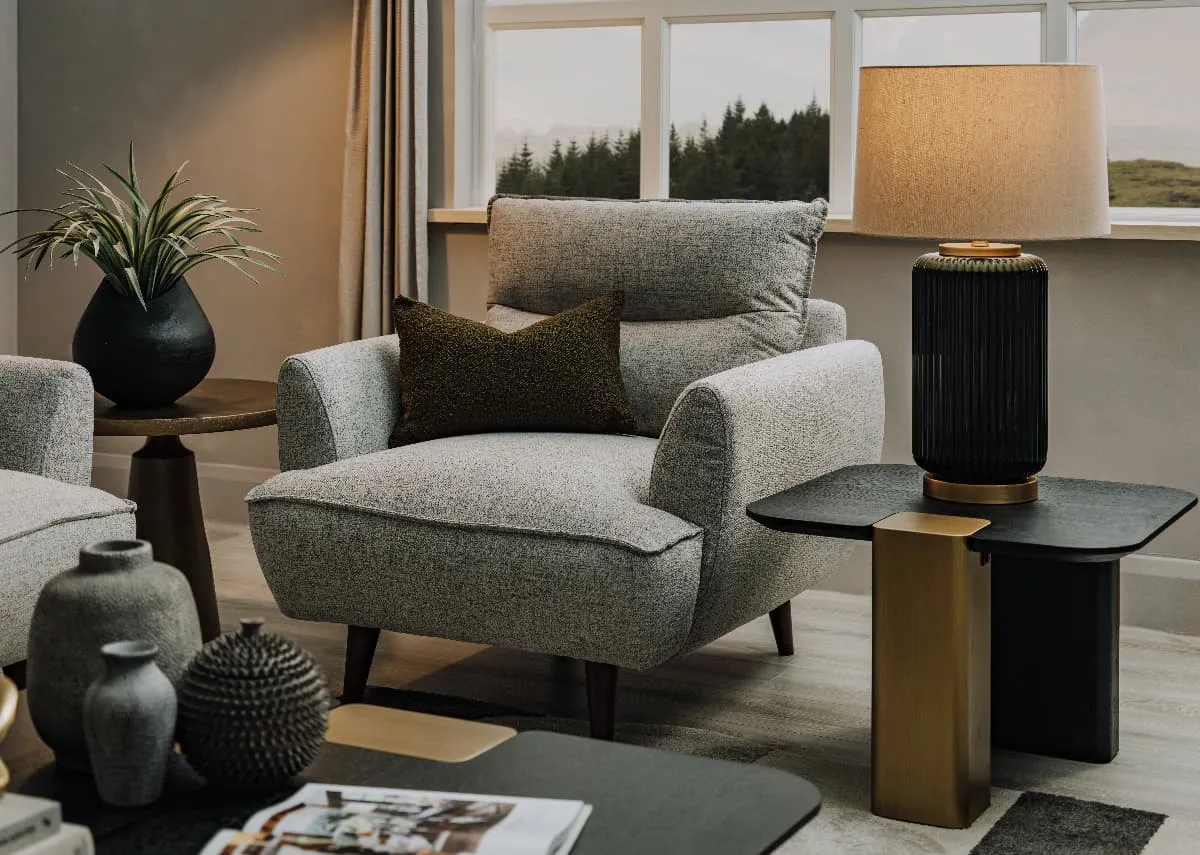 A lifestyle image of the Marlyn armchair with echo side table with Vail lamp switched on.