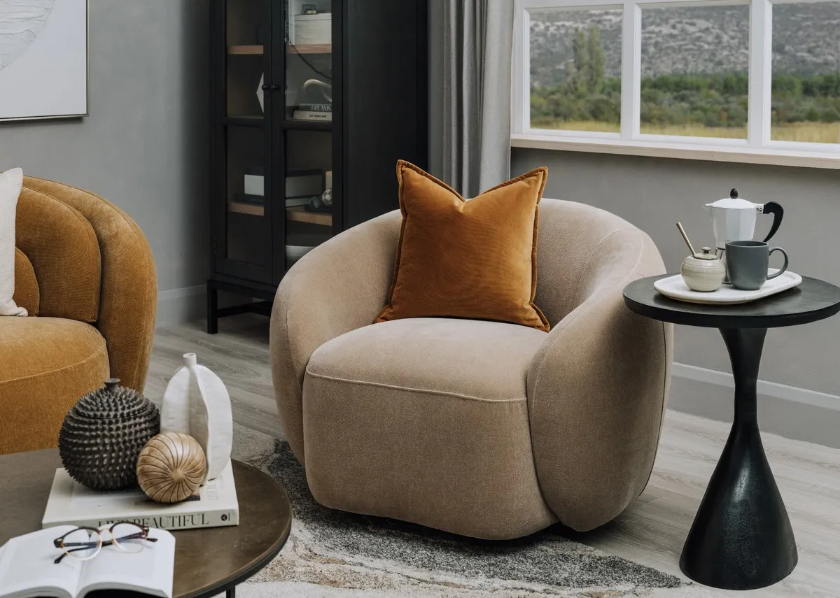 A lifestyle image of the Danica velvet swivel chair with the Bulan black side table.