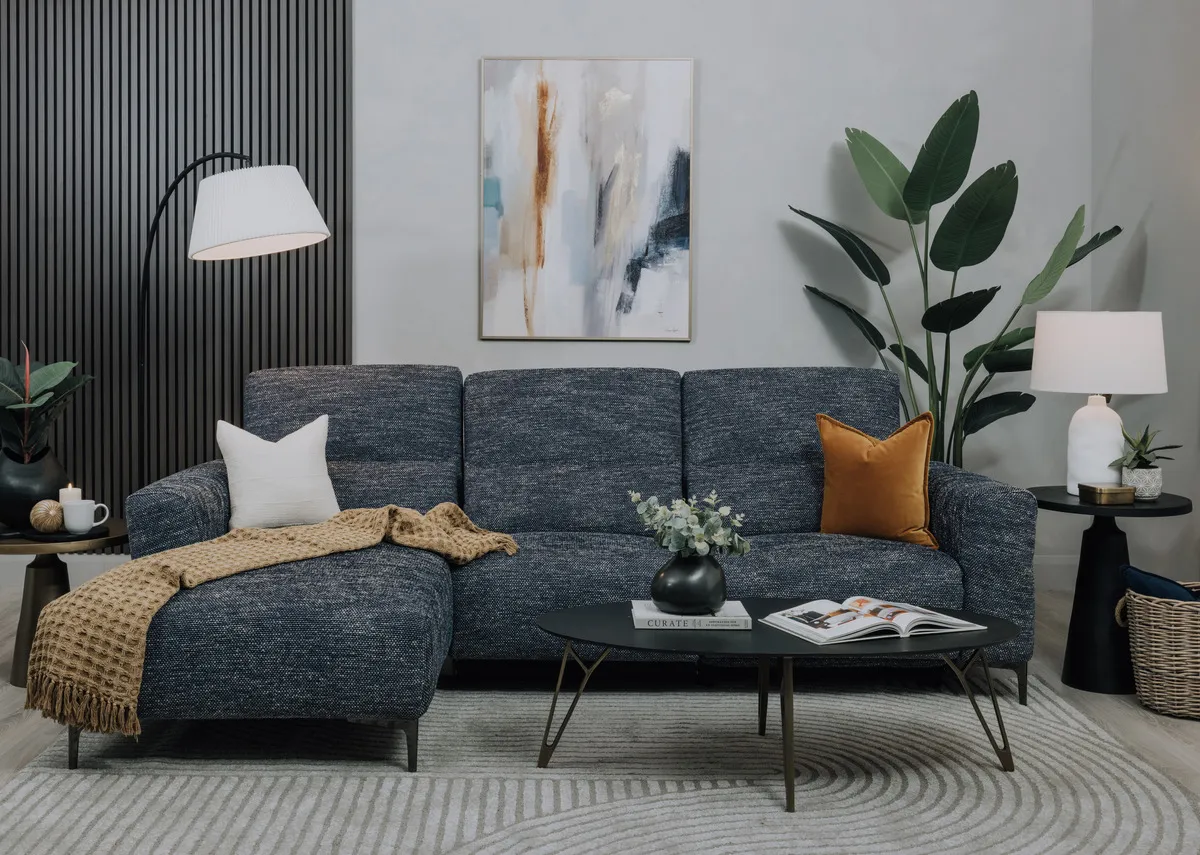 A lifestyle image of the Lincoln Corner chaise with Bayu coffee table with Inspired Canvas and slatted wall in black.