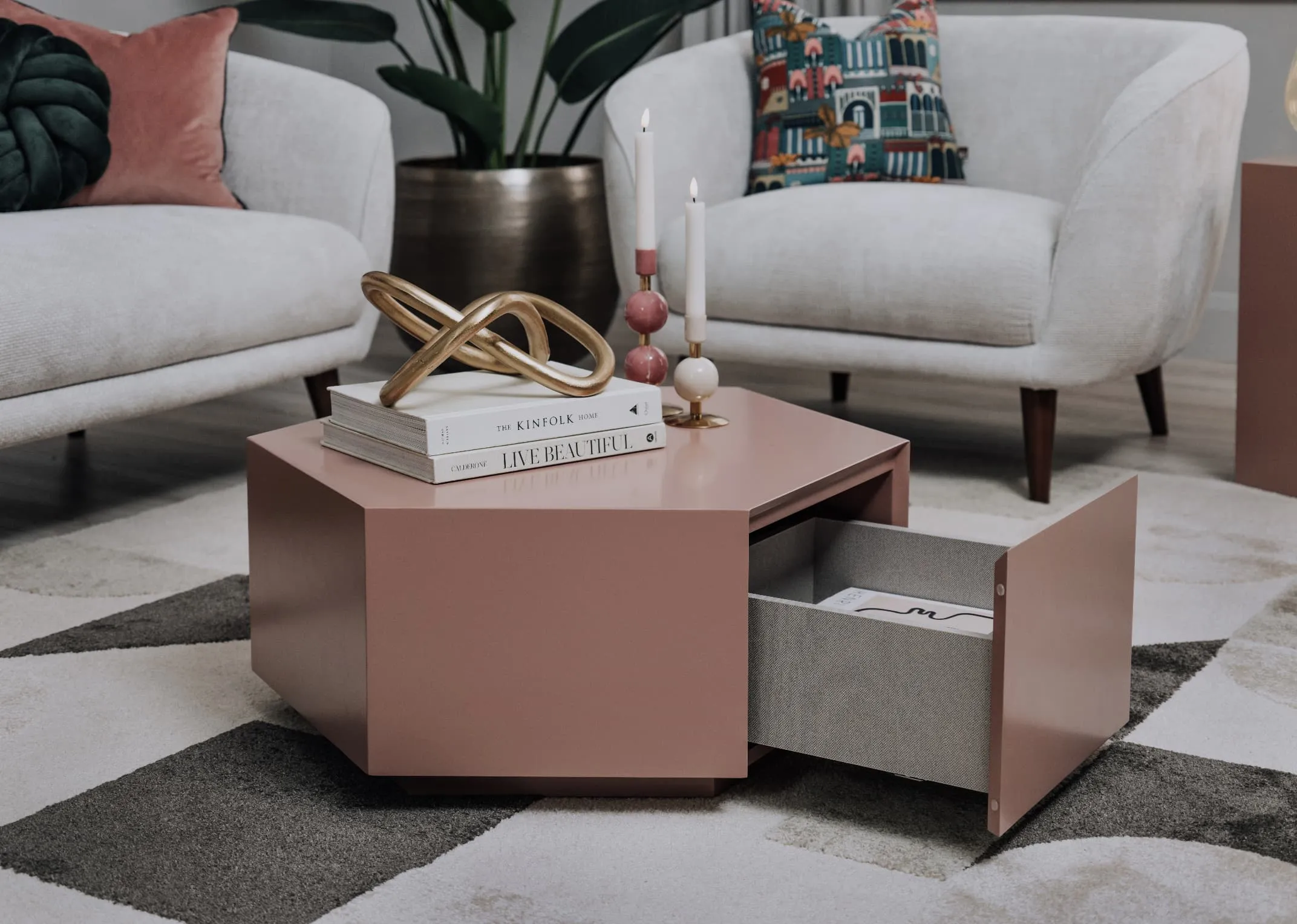 A lifestyle image of the Jonas coffee table with open drawer with books & candle holders on top with Amber armchair.