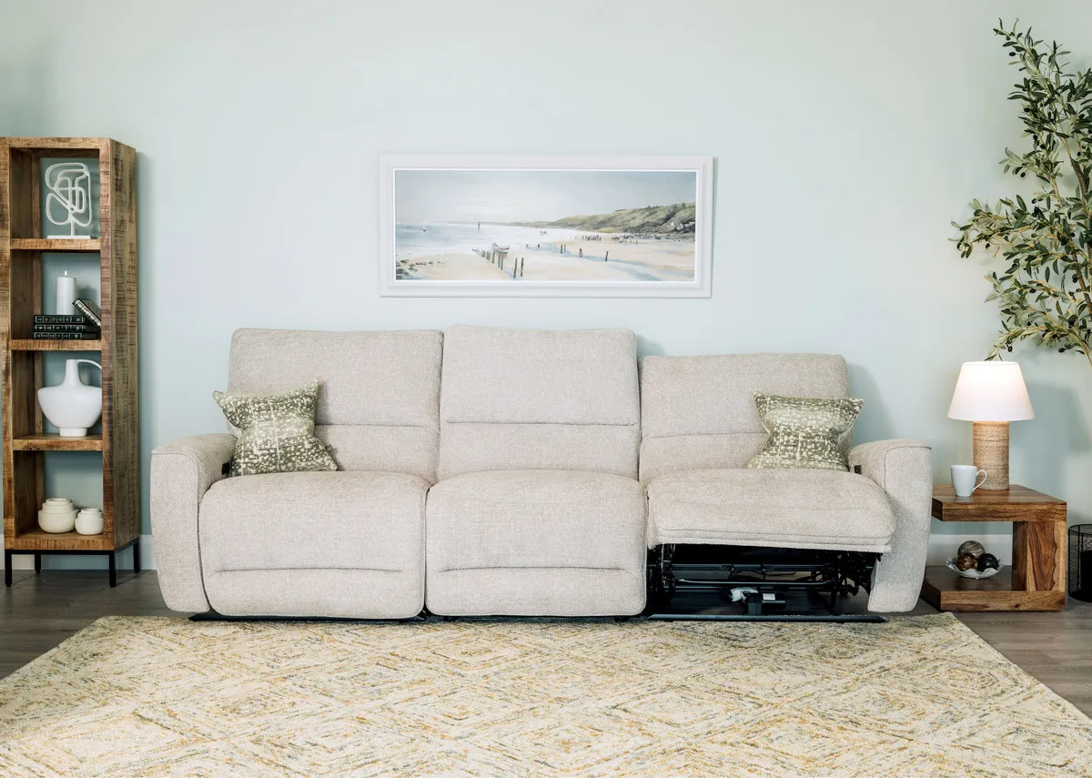 A lifestyle image of the Ashbrook sofa reclined with green cushions and Avoca bookcases.