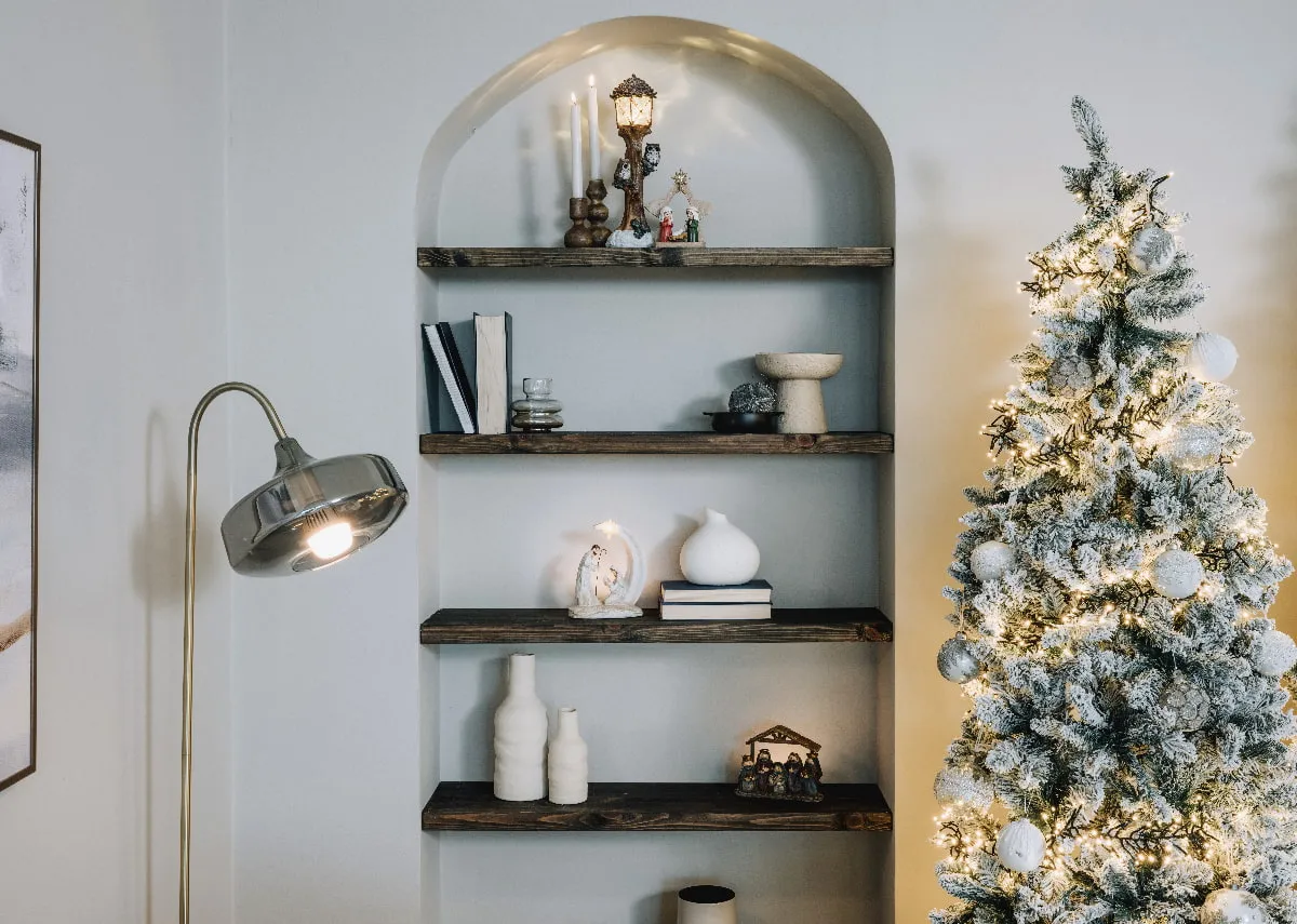 A lifestyle image of an alcove with shelves of Christmas ornaments with Noble Christmas tree.