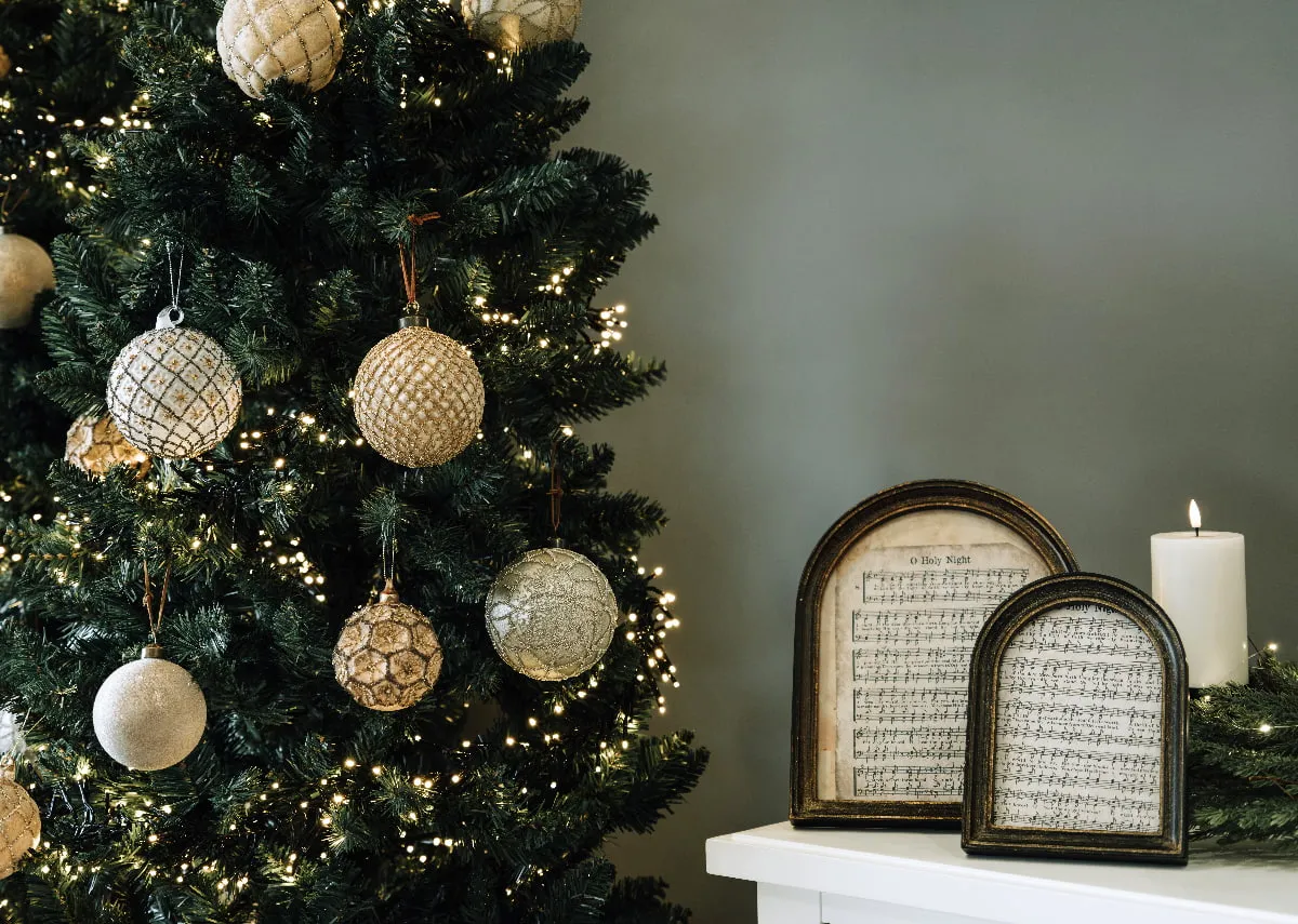 A lifestyle image of the Noble tree beside a mantle with Come on Ye Faithful bauble