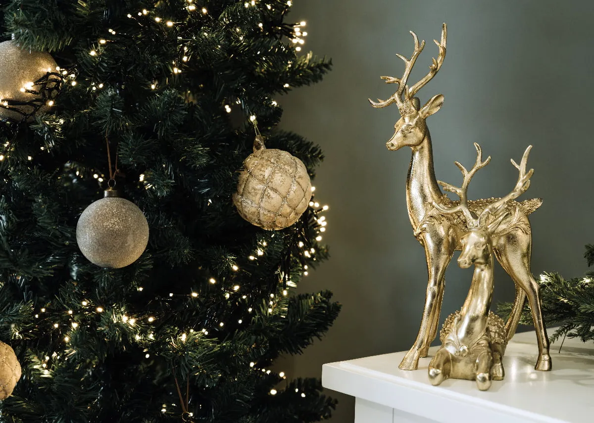 The Standing gold deers on a mantle beside a sherwood tree with gold All I want for Christmas bauble.