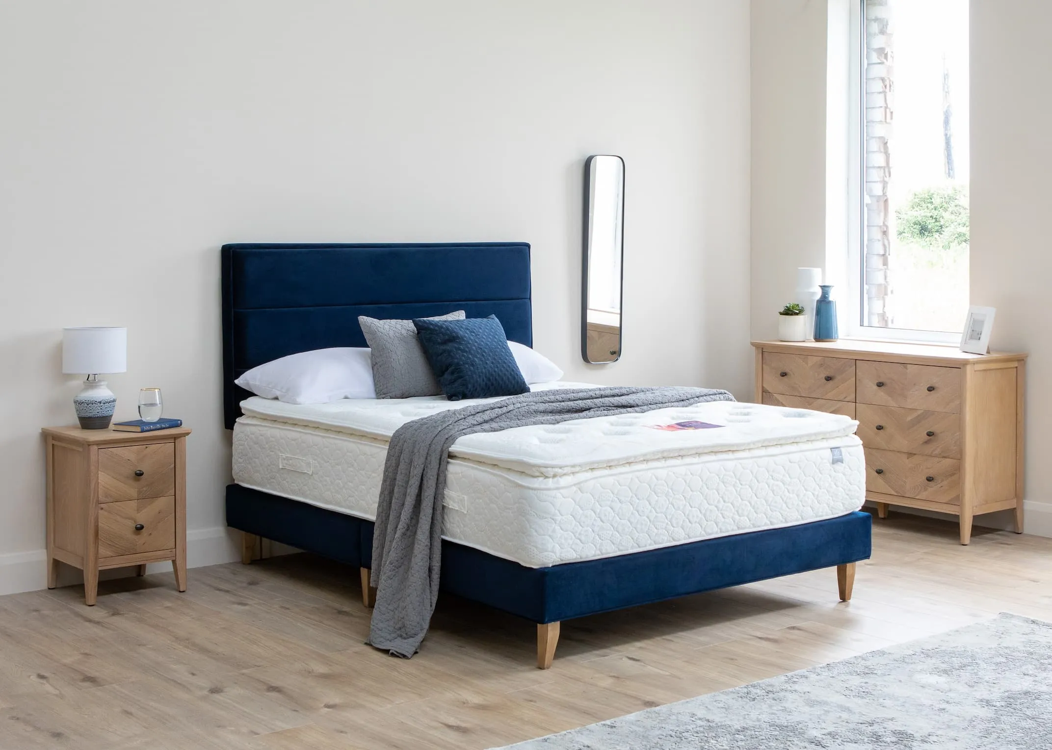 A lifestyle image of the Ebony Blue Velvet Bed base & headboard with chevron chest & Locker.