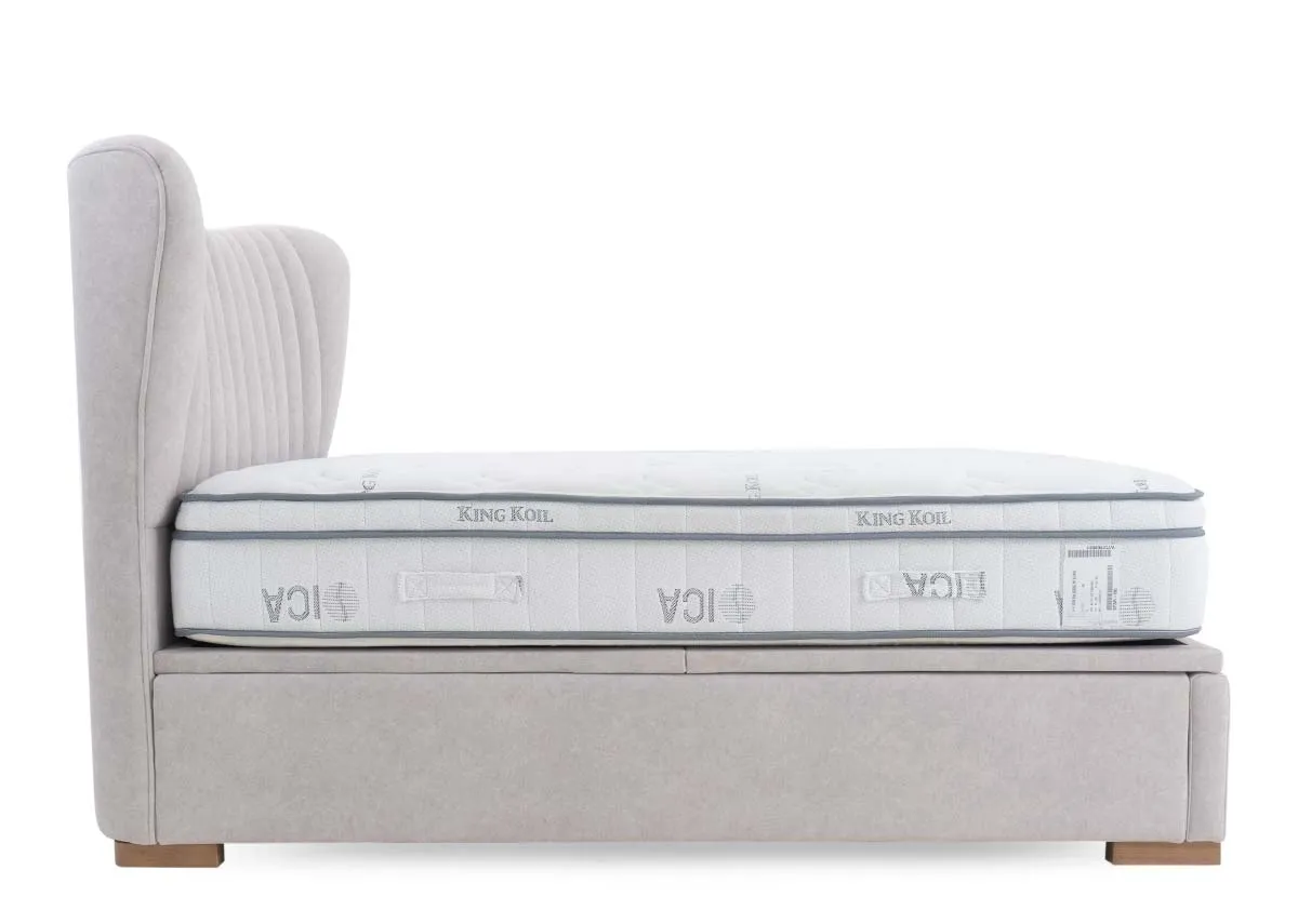 A light grey fabric ottoman bed with a white mattress on top showcasing its vertically tufted headboard and clean side profile.