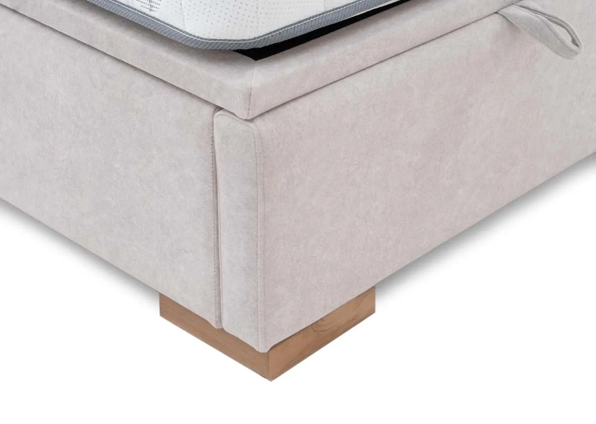 A close up view of the corner of the grey fabric bed base highlighting the soft upholstery texture and the square wooden foot.