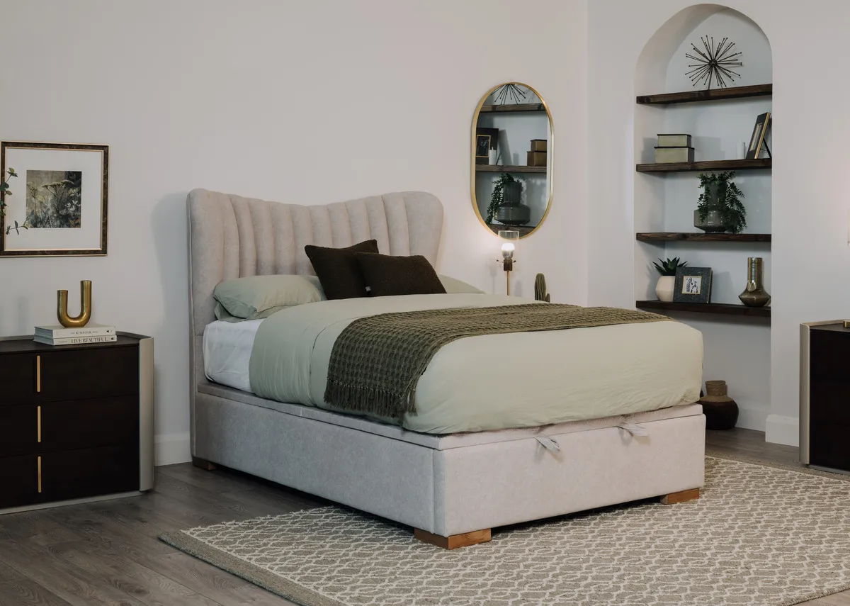 A lifestyle image of the Robin grey ottoman bed closed with mattress with heiny rug and Canna dresser.
