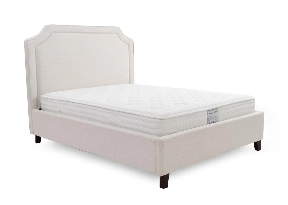 A beige fabric bed frame from EZ Livings Archie range. Angled view of upholstered sides and high headboard
