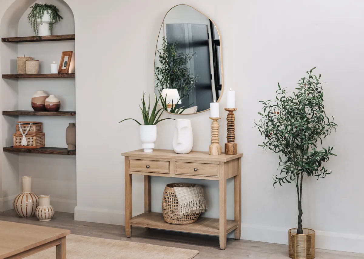 A lifestyle image of the Dawn console table with benton mirror with a selection of accessories and a basket on the lower shelf