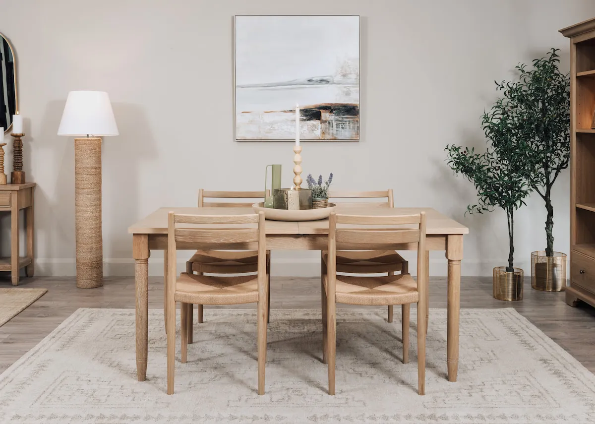 A lifestyle image of the Dawn extendable dining table with chairs and bookcase with Melody floor lamp and Shoreline framed print