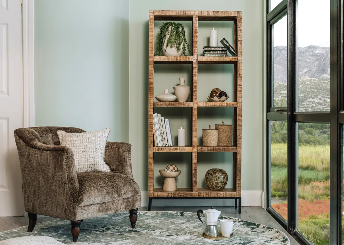 A lifestyle image of the Carter armchair on the Modesto rug with tall Avoca bookcase beside a window.