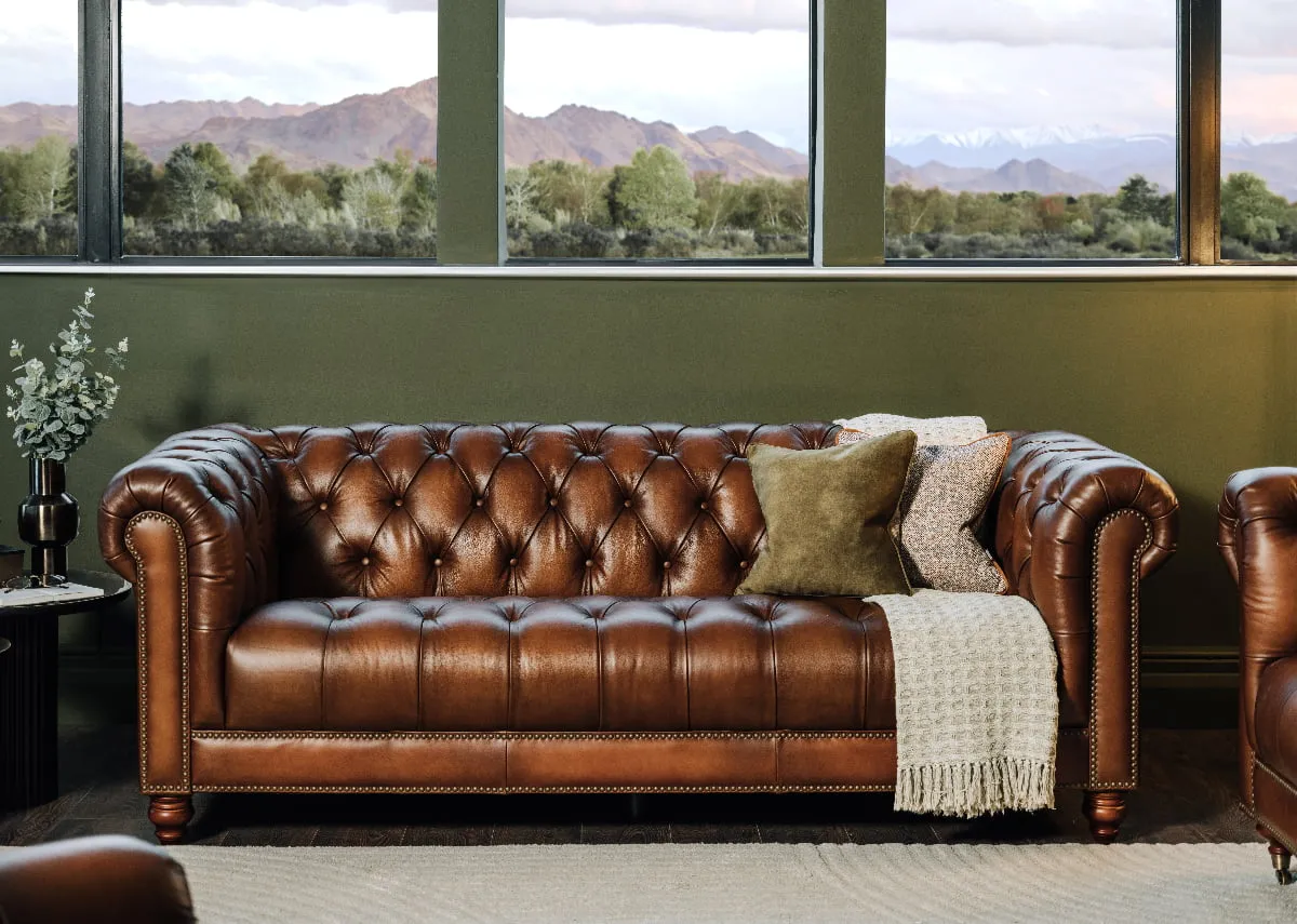 A 3.5 seater leather sofa with velvet cushions and a side table