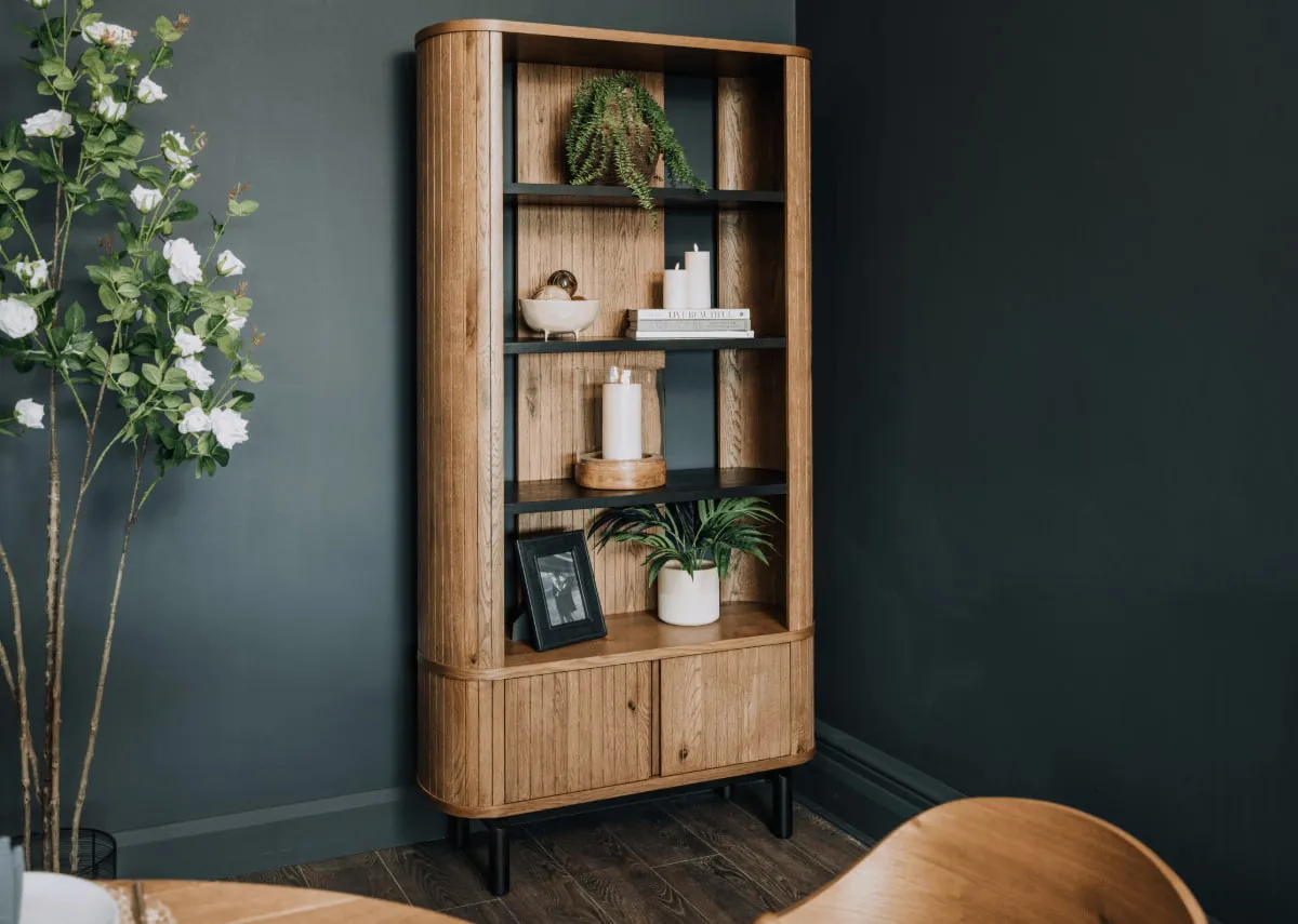 A lifestyle image of the Vega rustic bookcase with 2 lower drawers closed and shelves dressed with vases