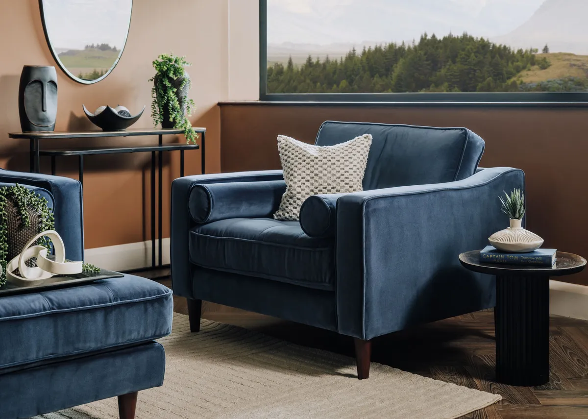 A lifestyle image of the Genoa armchair with side table and matching footstool.