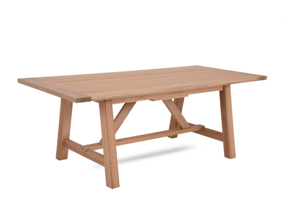 An oak dining table from EZ Livings Albany range. Angled view of the thick wood top and trestle base.