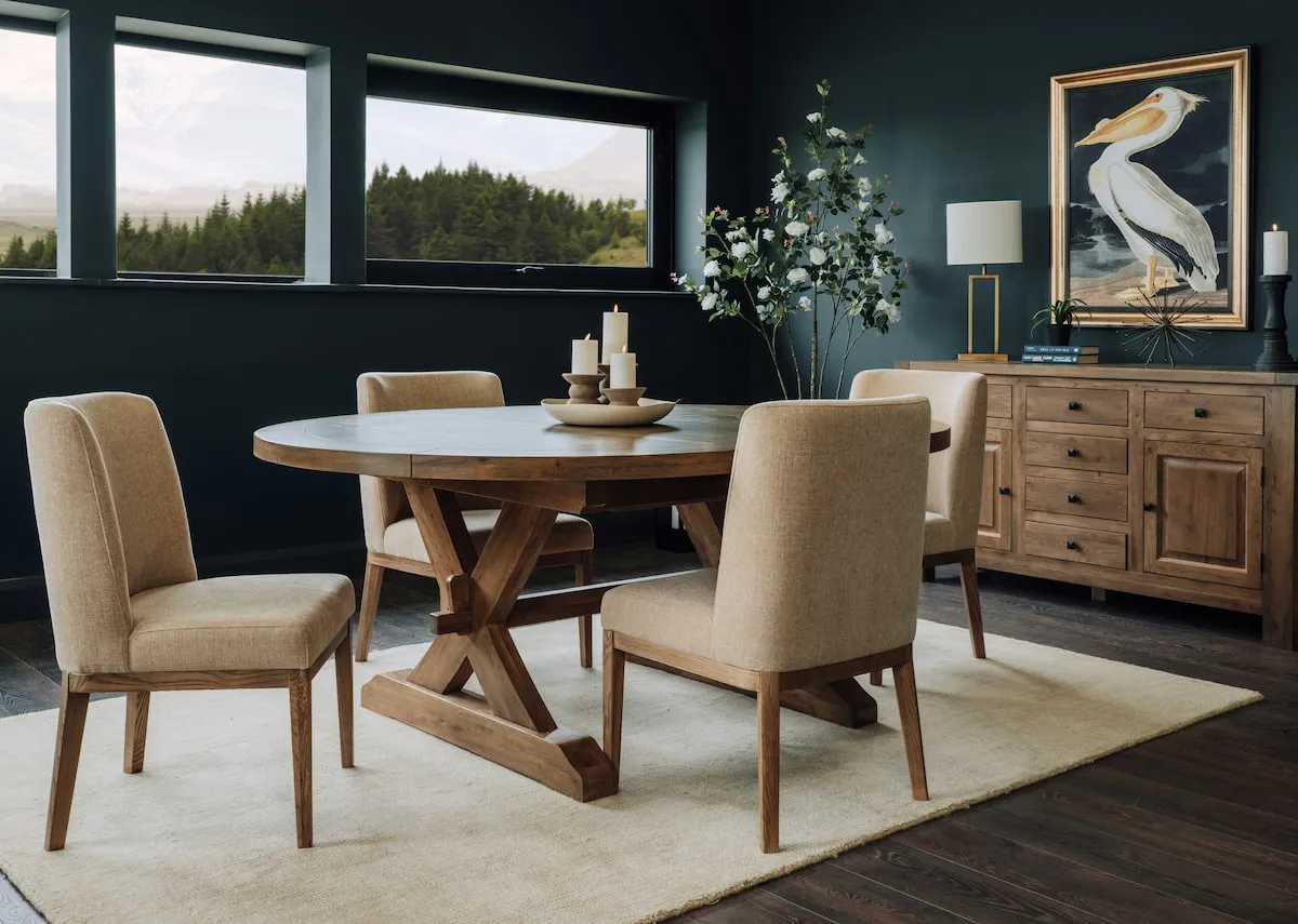 A lifestyle image of the Naxos round table with fabric cream chairs and sideboard with Pelican print.