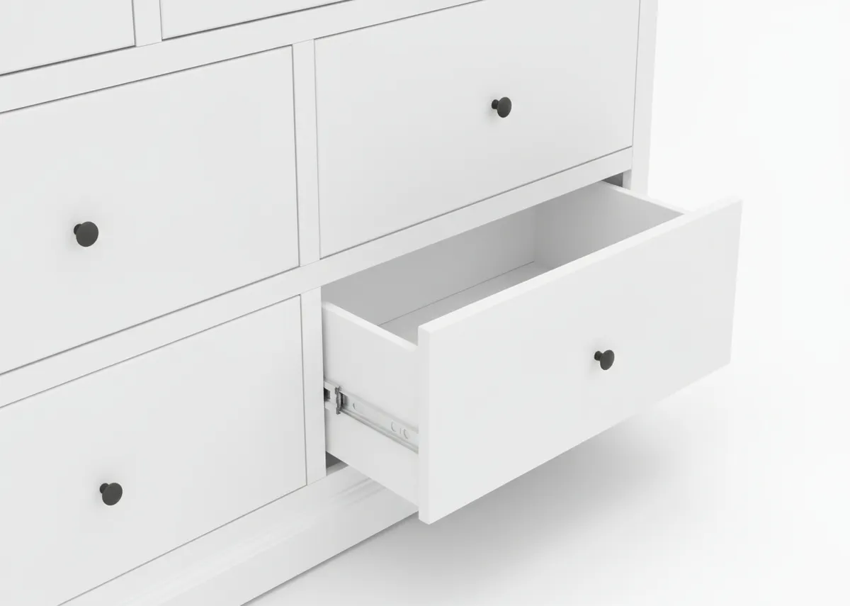 A close up view of the bottom right drawer of the white chest of drawers partially open and revealing the smooth runners.