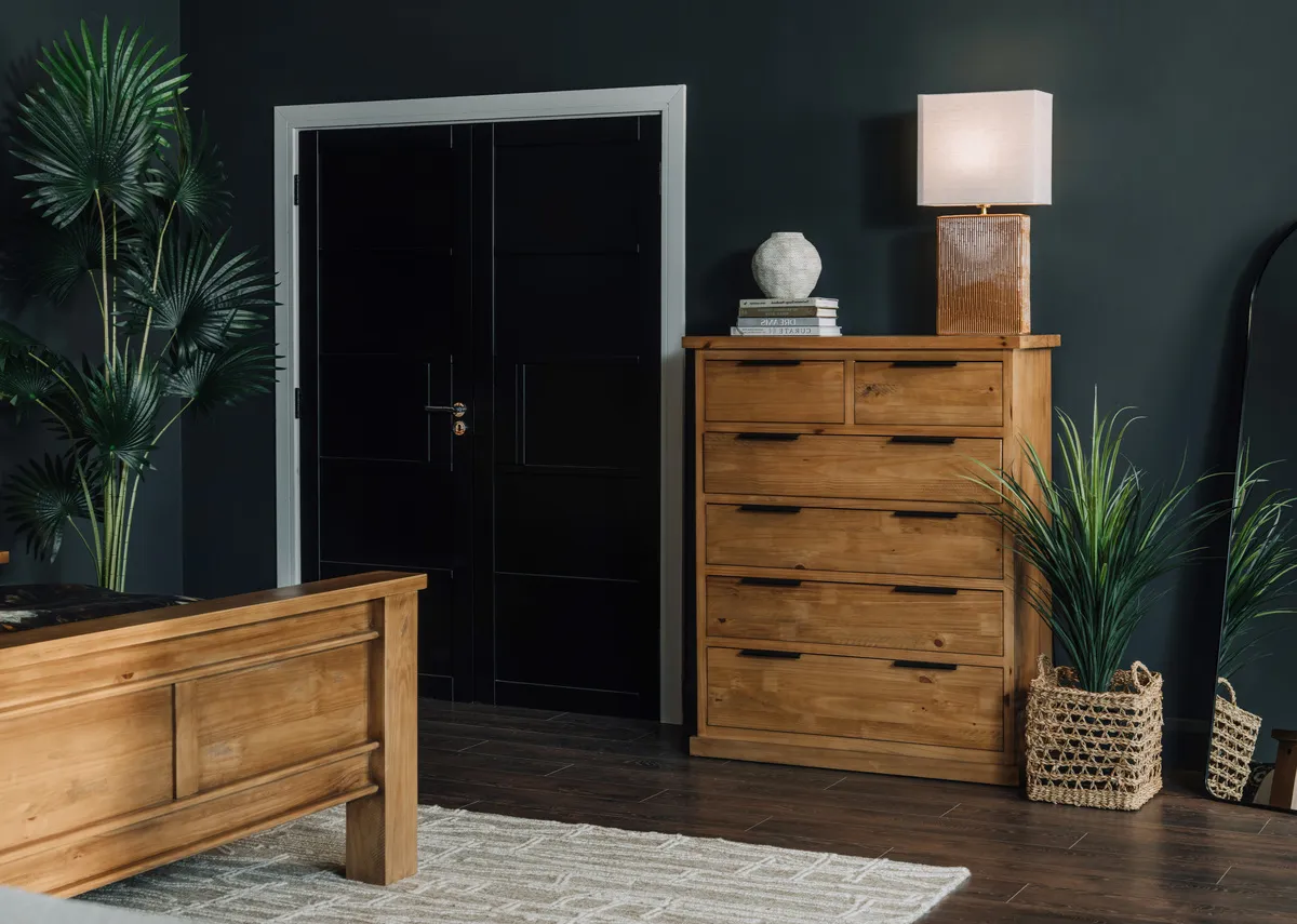 A lifetsyle image of the Pine Creek bedroom chest with Dee lamp and Yucca plant in basket.