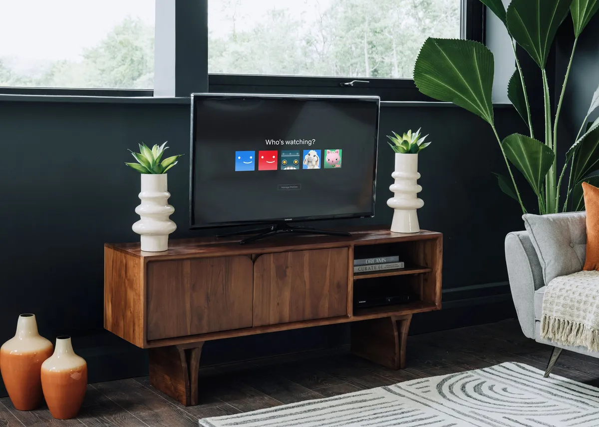 A lifestyle image of the TV Unit with doors closed and tv set with vases either side