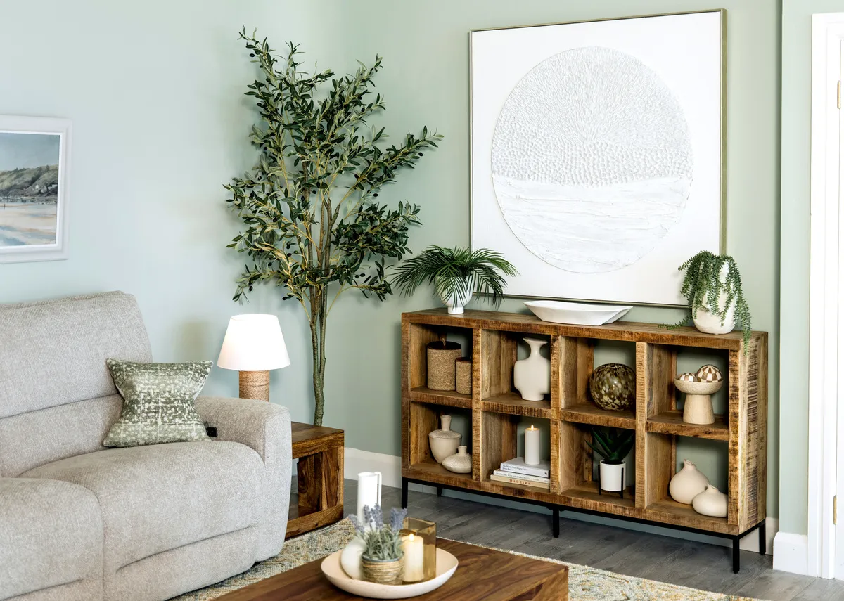 A lifestyle image of the Avoca bookcase with a selection of ornaments and vases with the Ashbrook sofa