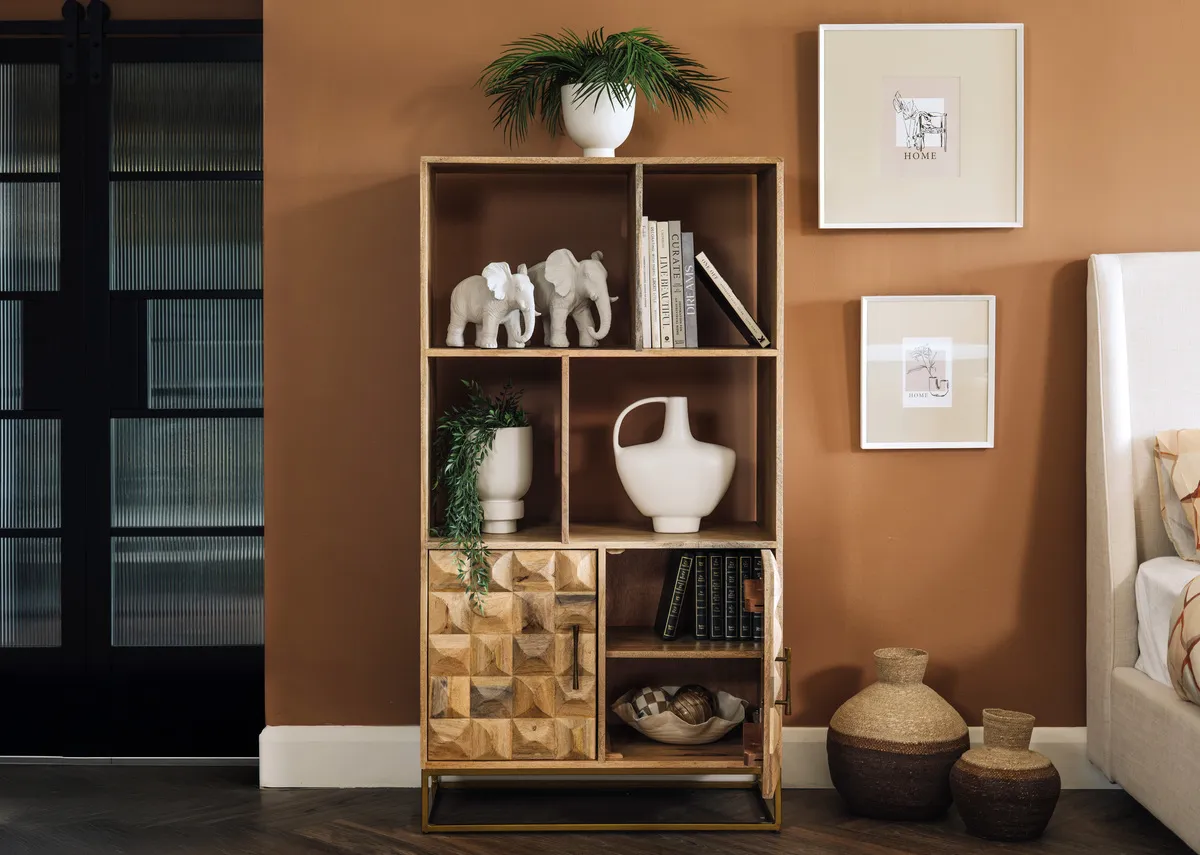 A lifestyle image of the Diva bookcase dressed with ornaments and vases with lower door open
