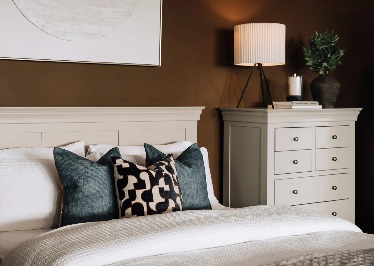 A lifestyle image of the Carter cushion on the Dove bed and chest.