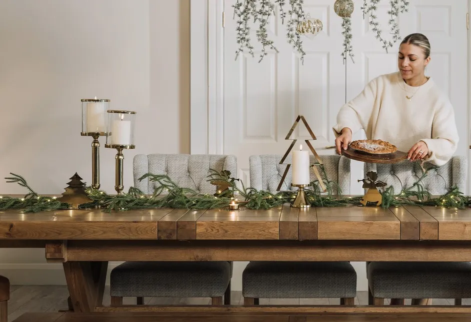 A lifestyle image of the Naxos dining table witha a selection of gold ornaments and candle holders.