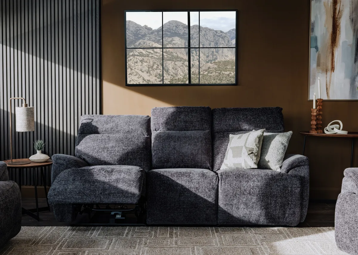 A lifestyle image of the Mallow charcoal 3  seater in recline mode with Inspired canvas and Memphis rug.