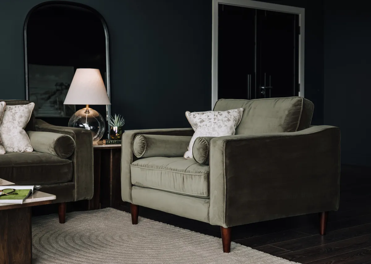 A lifestyle image of the Genoa green armchair with Ethel table lamp.