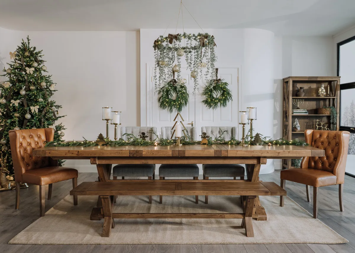 A lifestyle image of the Tommy leather dining chair with the Naxos dining table and  bench with Christmas tree!