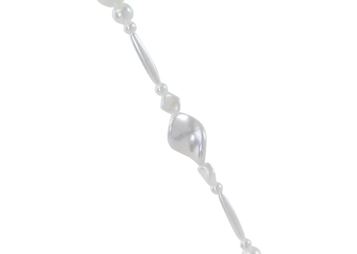 A close up showing the cream large pearl garland featuring round elongated and irregular shaped pearls on a white string.