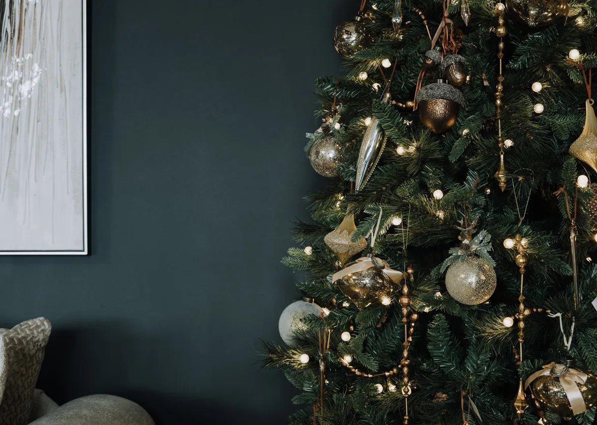 A lifestyle image of the Aspen christmas tree with a slection of brass and gold decor including the brass garland.