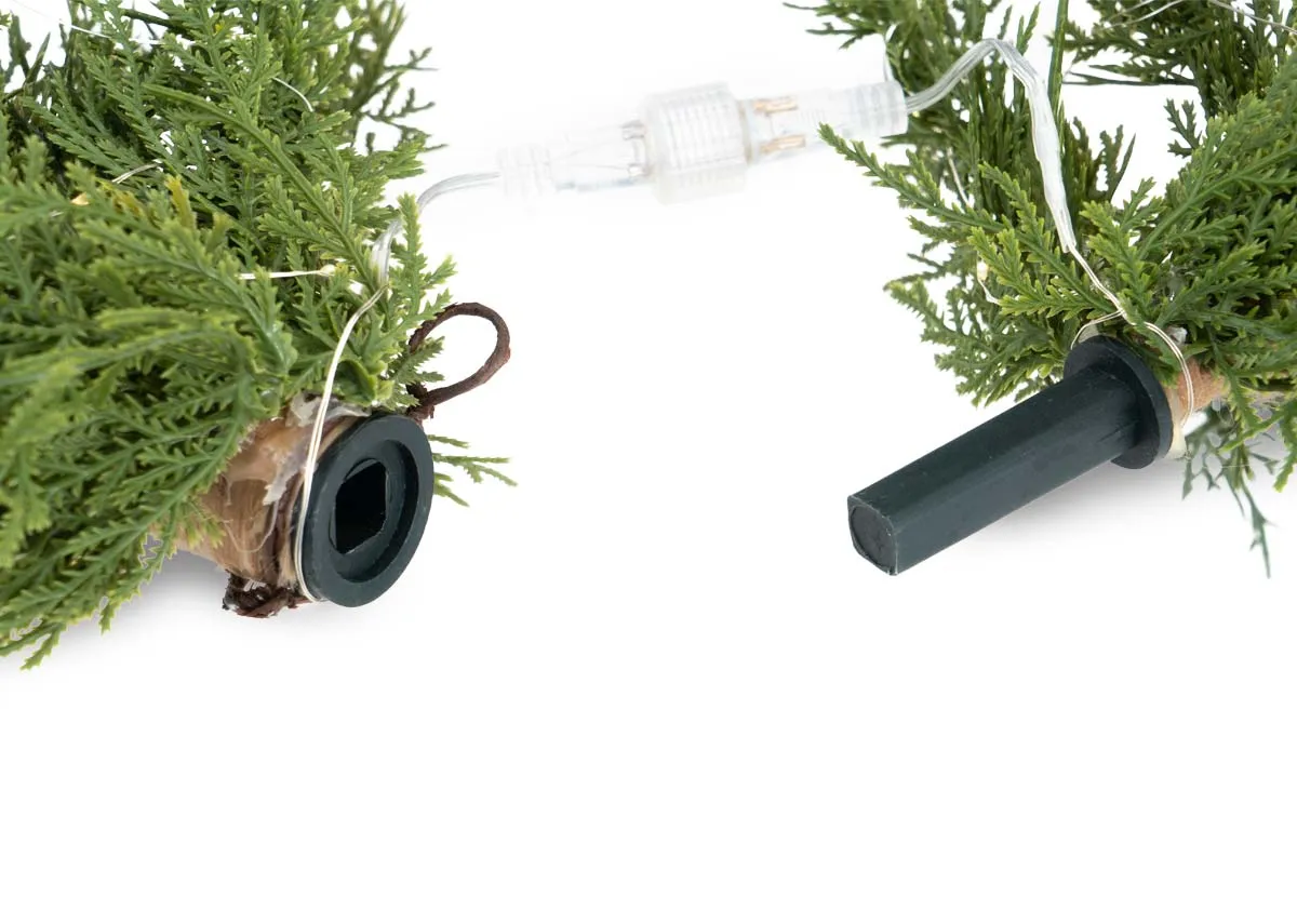 A close up of the connection point of the garland with lights showing the interlocking end pieces of the green foliage.