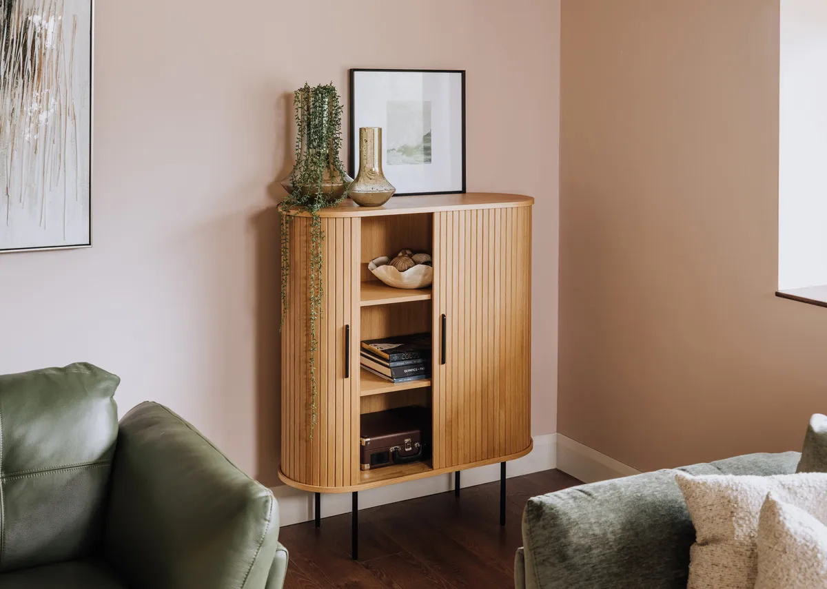 A lifestyle image of the Nola Oak cabinet open with tones of grey pic and toscana sofa.