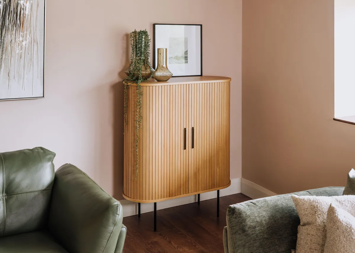 A lifestyle image of the Nola Oak cabinet closed with tones of grey pic and toscana sofa.