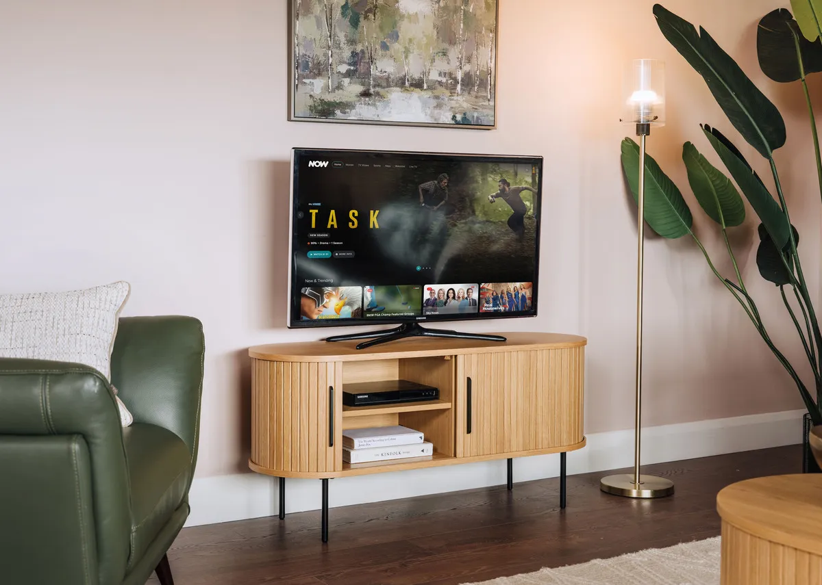 A lifestyle image of the Nola TV Unit open to show hidden storage with tv and Leanne lamp.