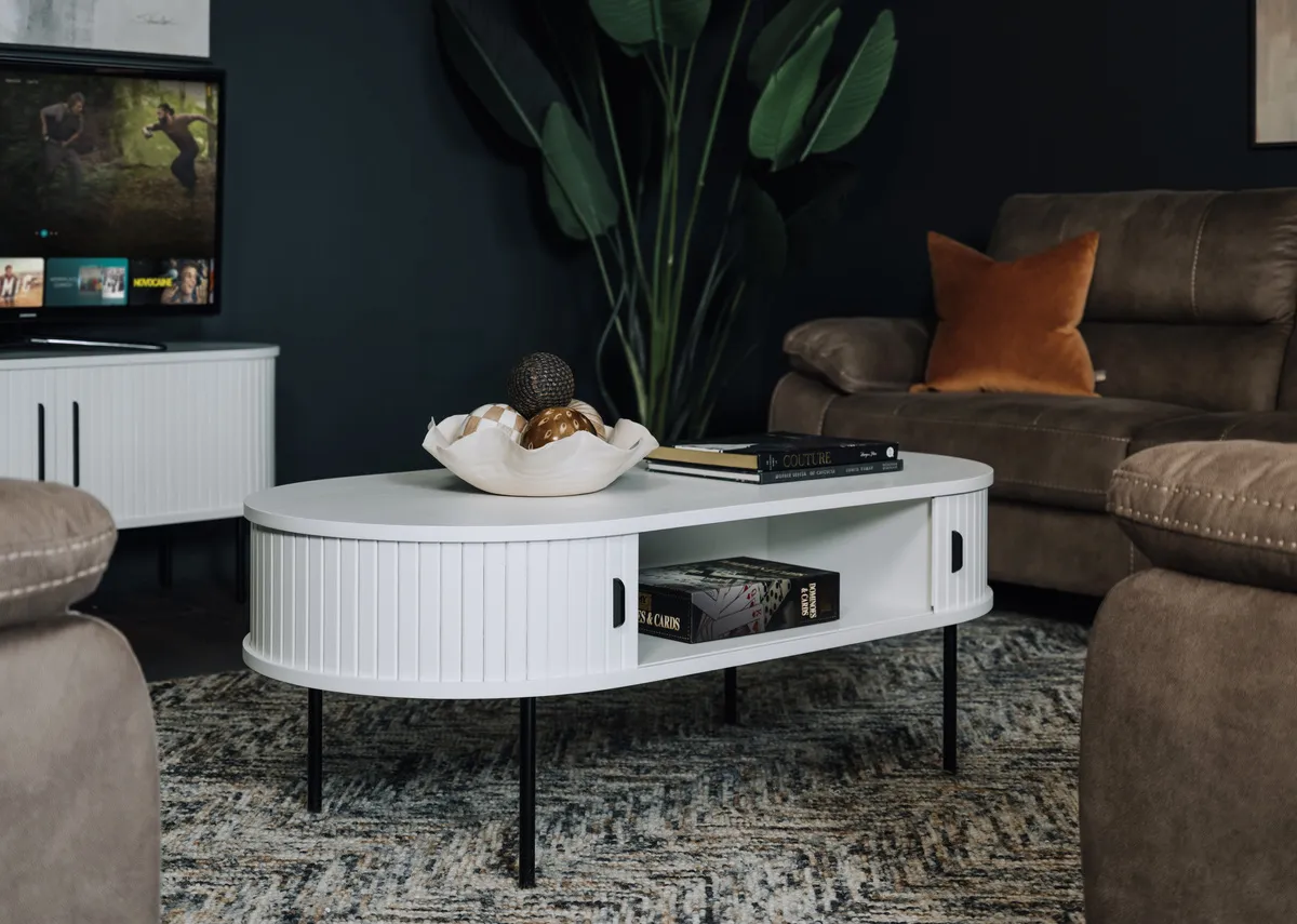 A lifestyle image of the Nola white oval table with doors open showing storage.