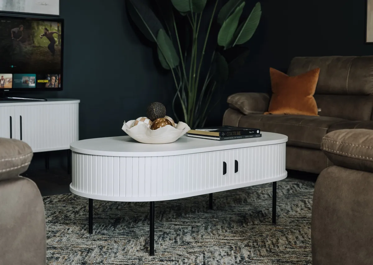 A lifestyle image of the Nola white oval table with doors closed with Nikita sofas and Savannah rug