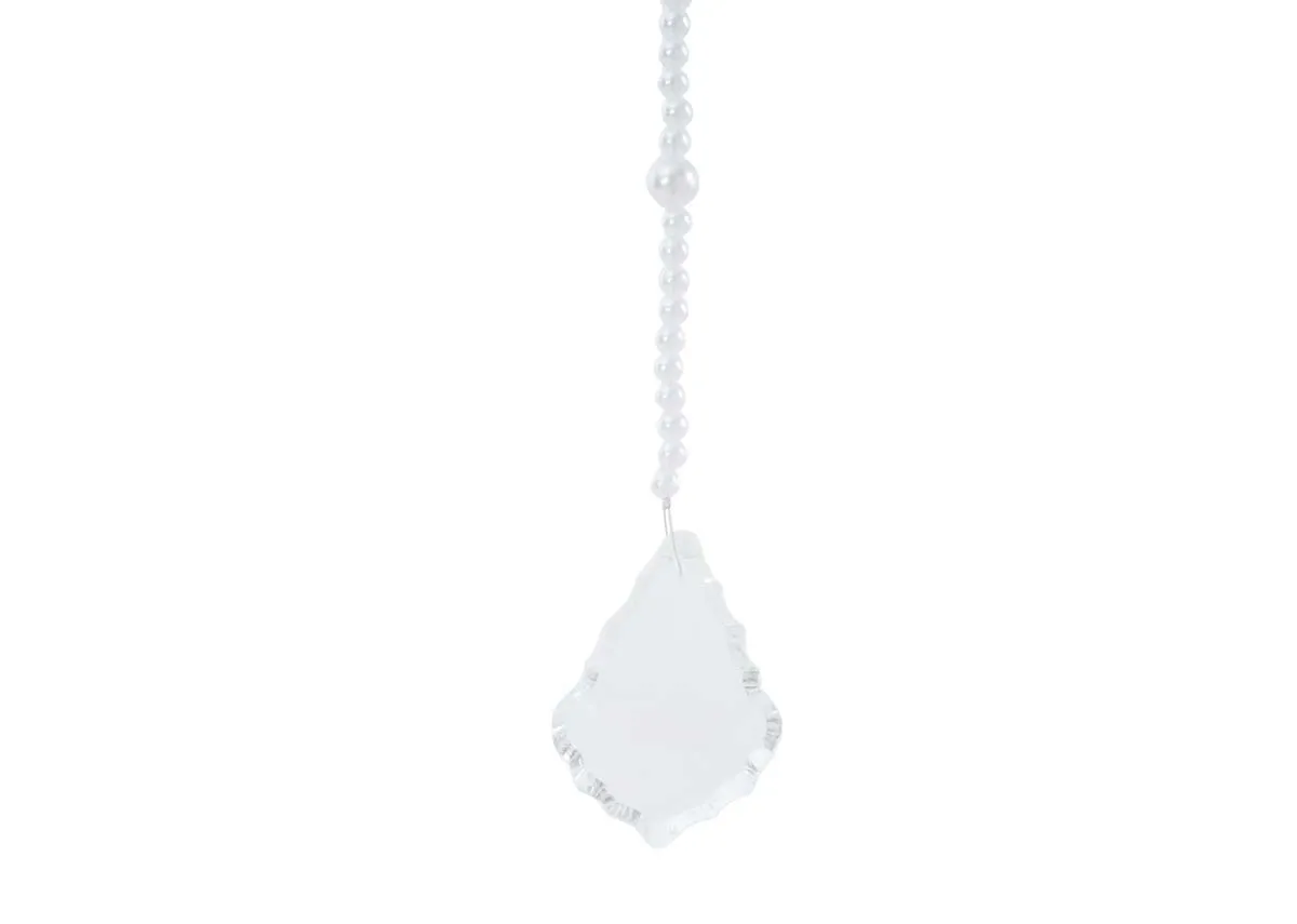 A close up of the large faceted irregular clear crystal drop on a white pearl crystal garland showing its intricate cuts.