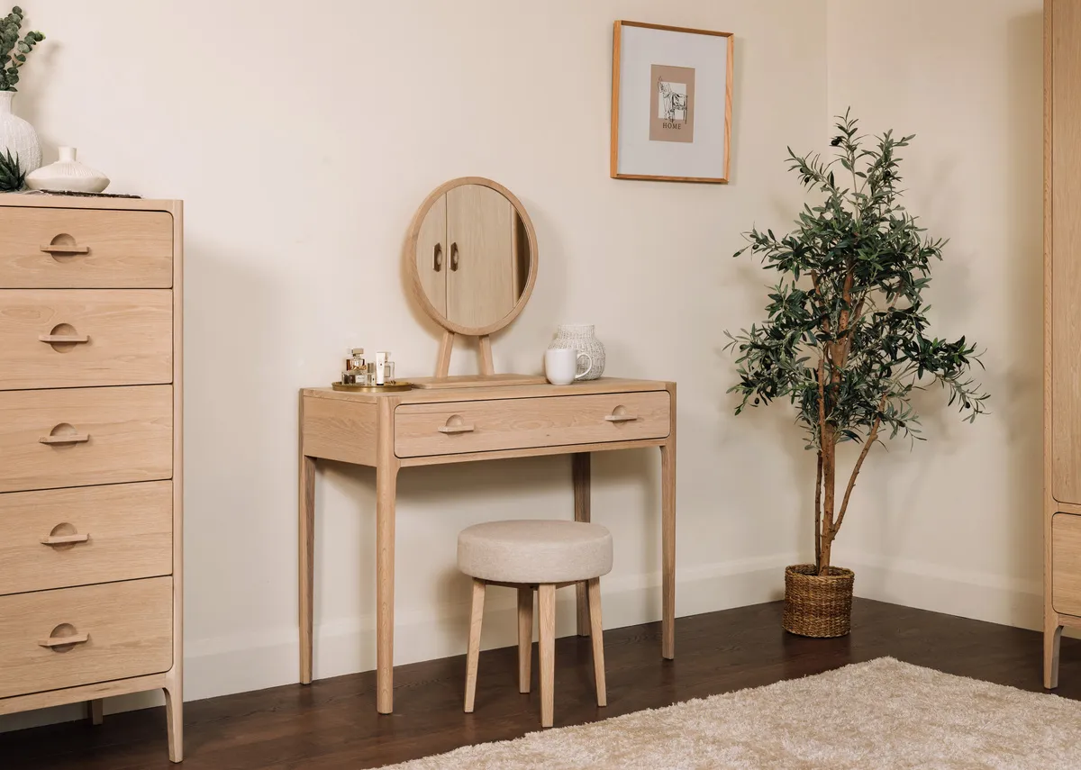 A lifestyle image of the Jay Dressing table and stool set with Olive plant.