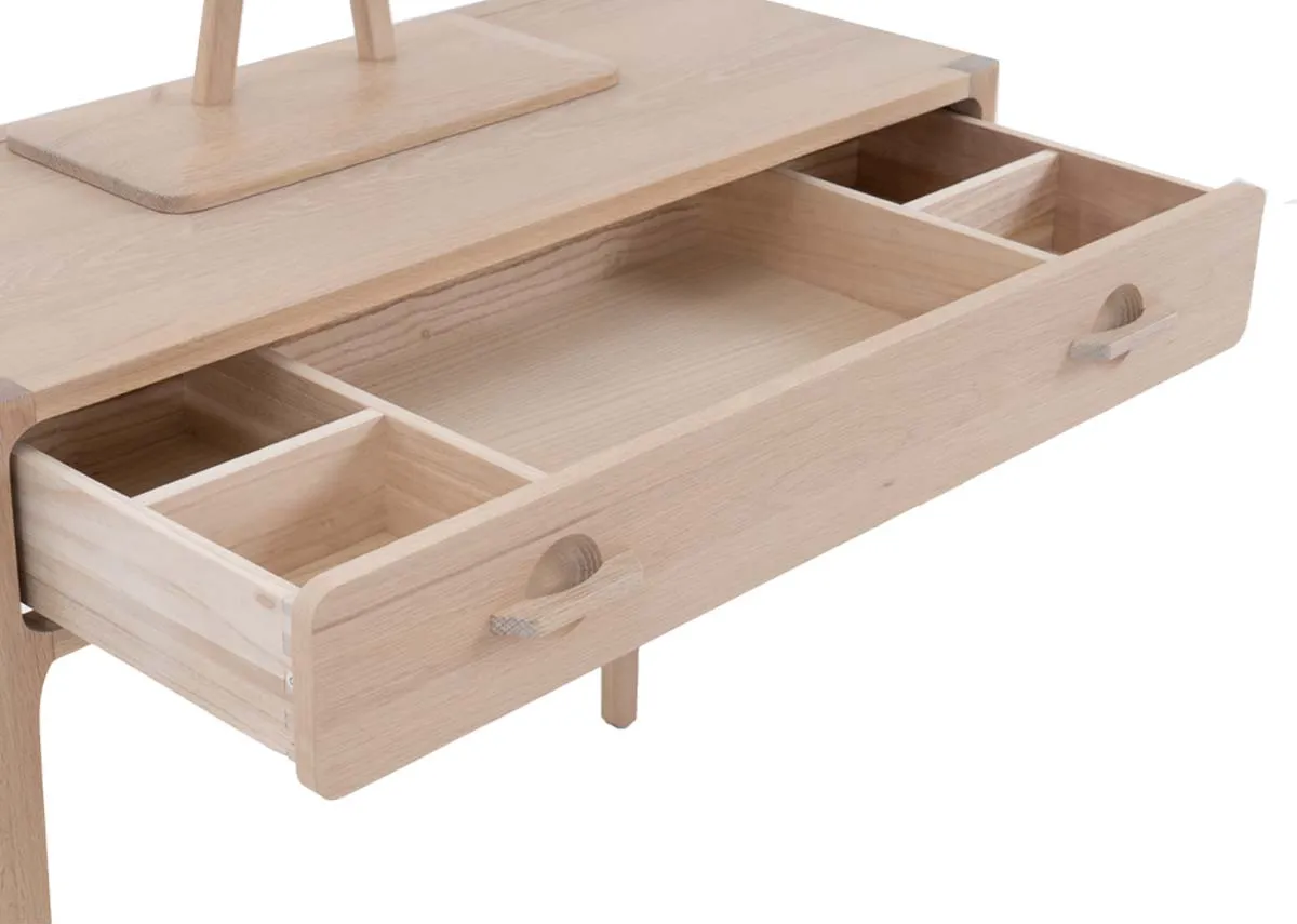A white oak dressing table with 1 large drawer and round mirror with a grey fabric stool. Closeup of drawer open with sections for makeup or jewellery