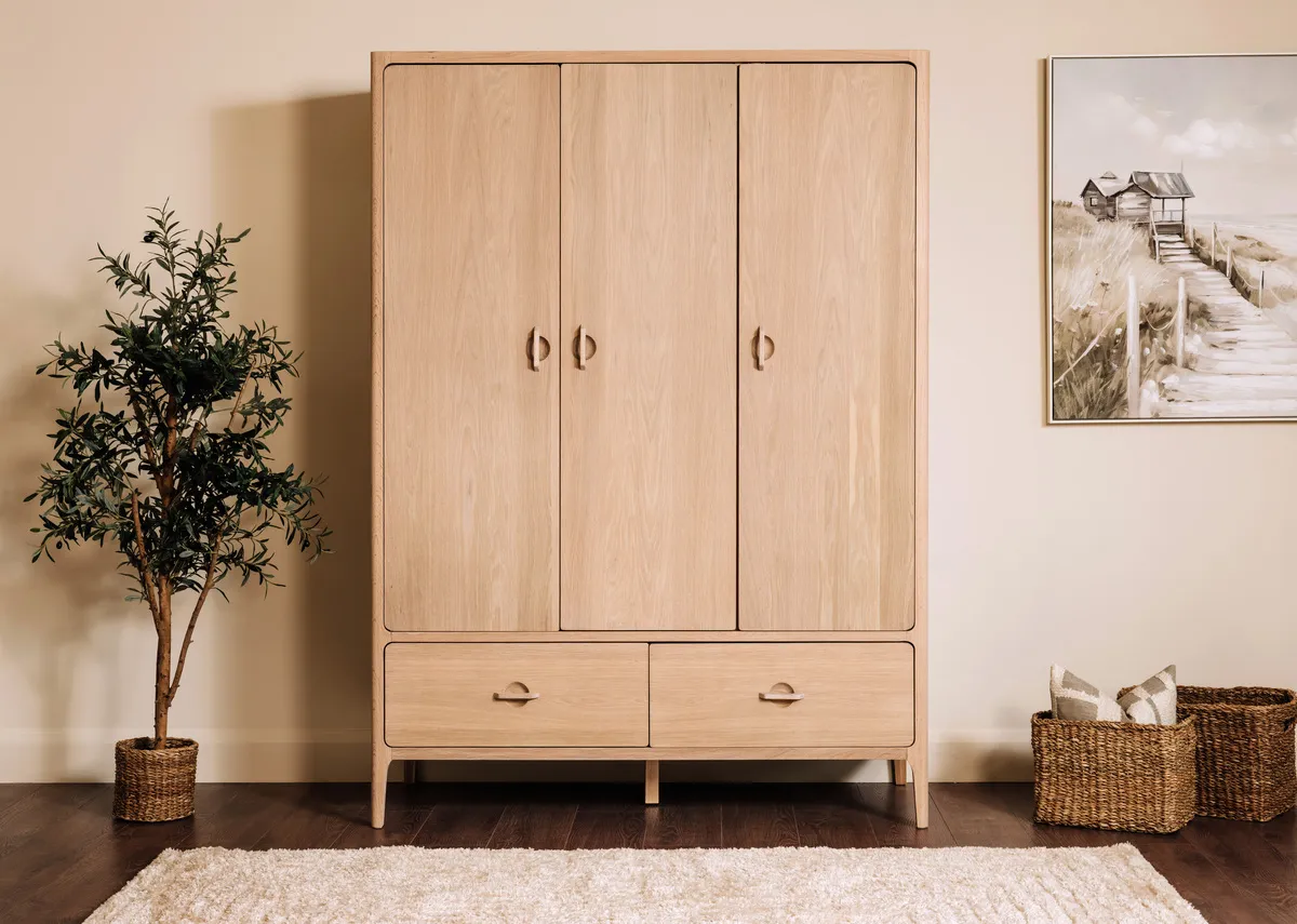 A lifestyle image of the Jay wardrobe with doors closed with Olive plant.