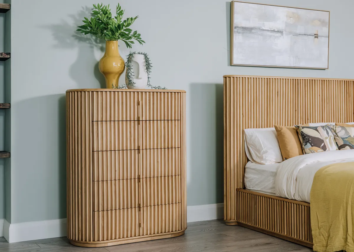 A lifestyle image of the Bradley Tallboy with bed and yellow vase.
