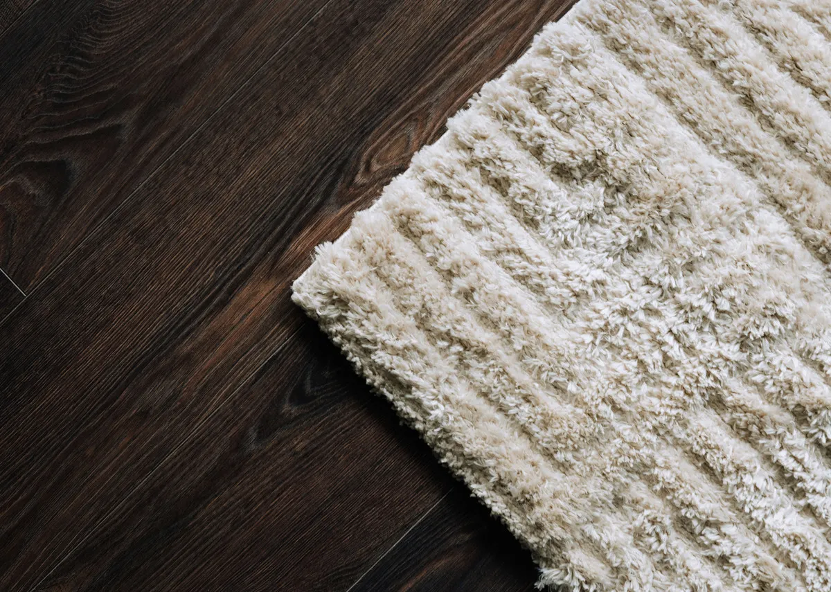 A lifestyle image of the Mosaic rug on a dark wooden floor.