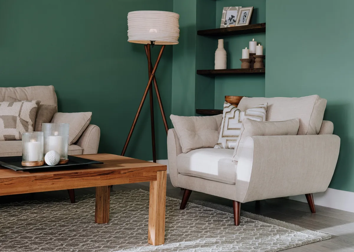 A lifestyle image of the Cardinal candle holder in large and small on a wood coffee table with Caoimhe armchair