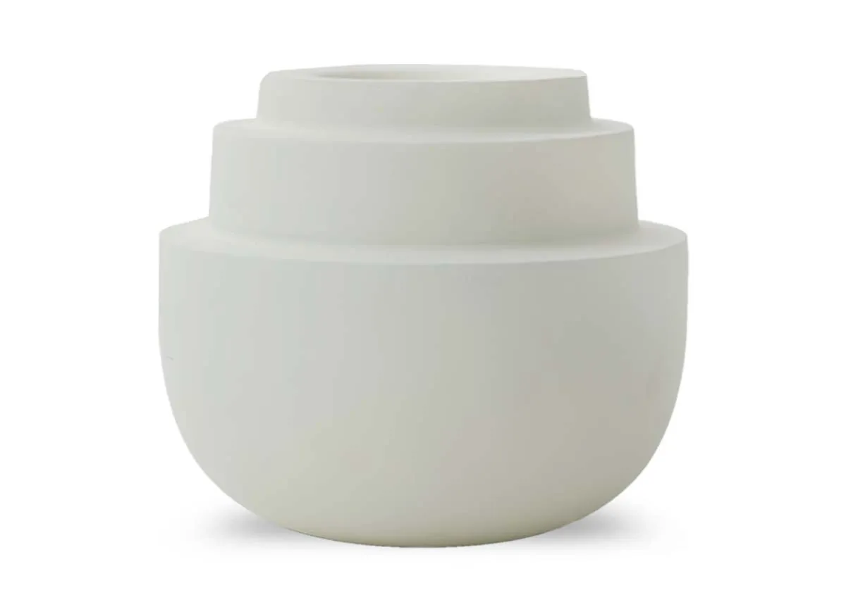 A small matt cream tealight holder with a rounded base and three concentric tiered sections on top shown at an angle.